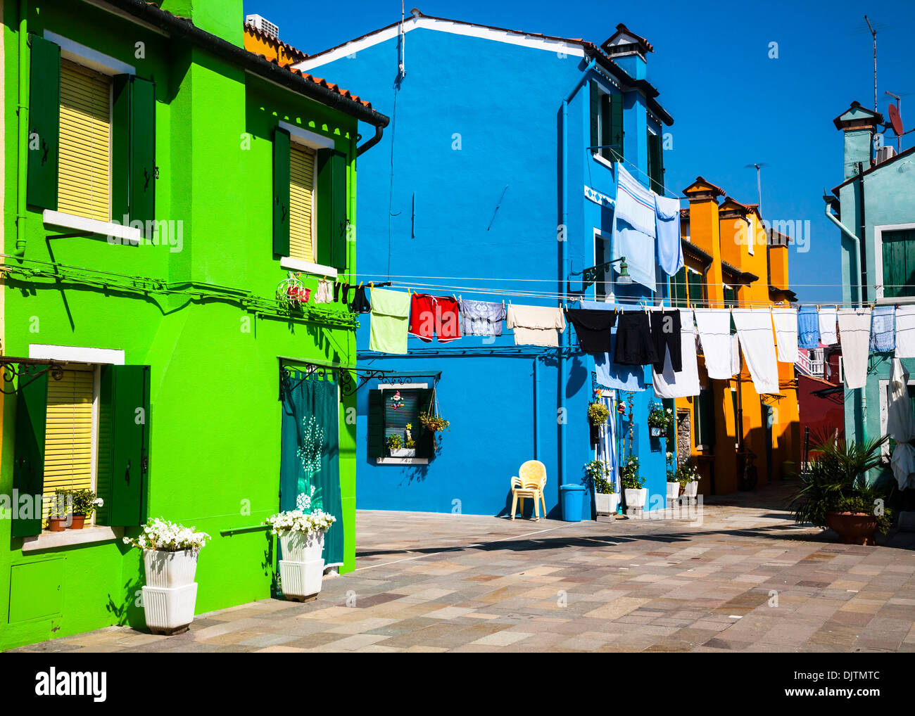 Case vivacemente colorate con vestiti di essiccazione al sole, l'isola di Burano, Veneto, Italia. Foto Stock