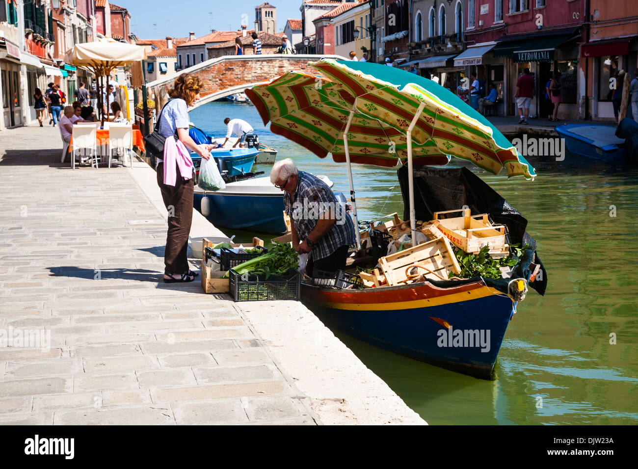 L'uomo per la vendita di frutta e verdura da una barca sul canal, Murano, Venezia, Veneto, Italia Foto Stock