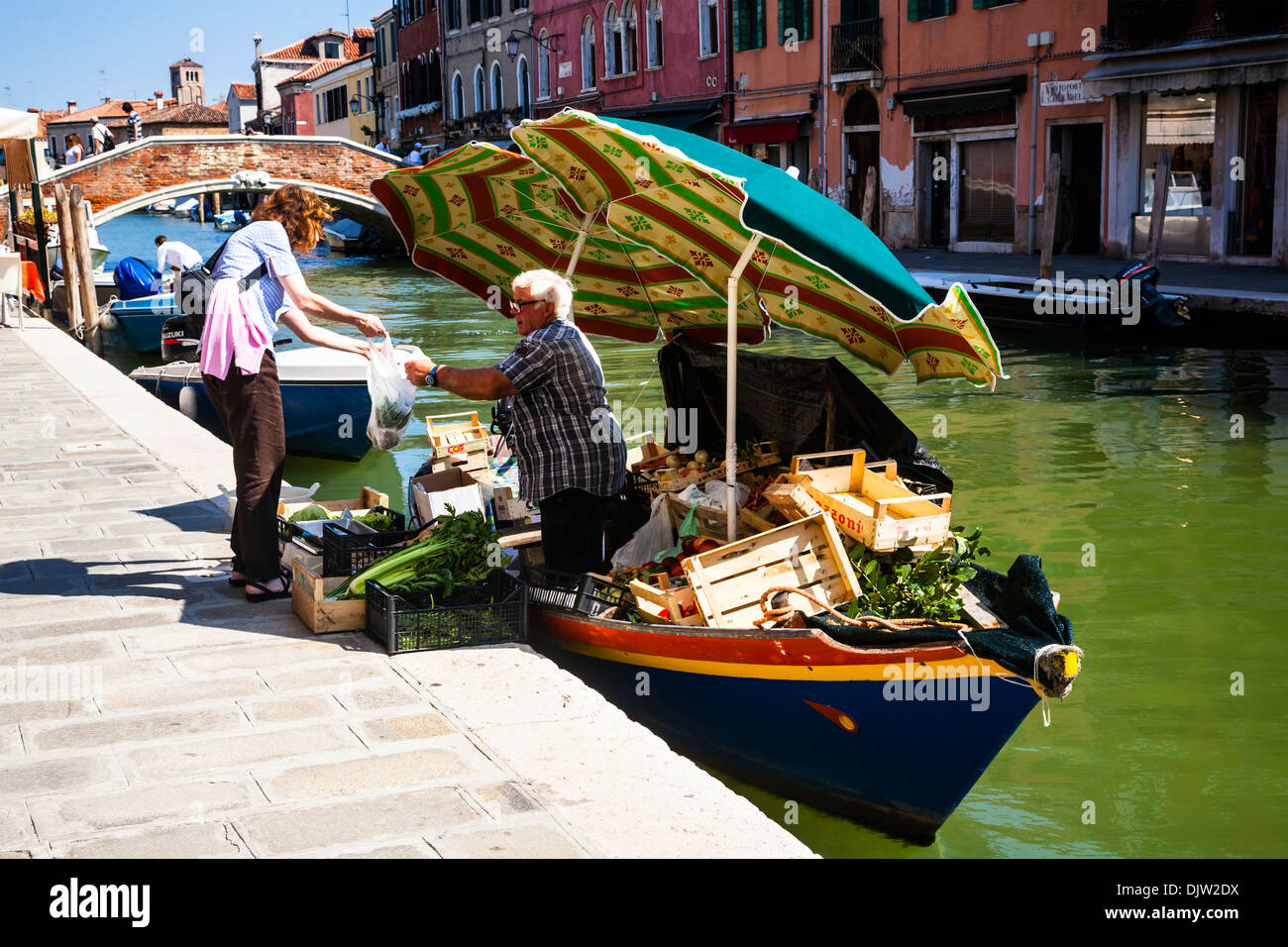 L'uomo per la vendita di frutta e verdura da una barca sul canal, Murano, Venezia, Veneto, Italia Foto Stock