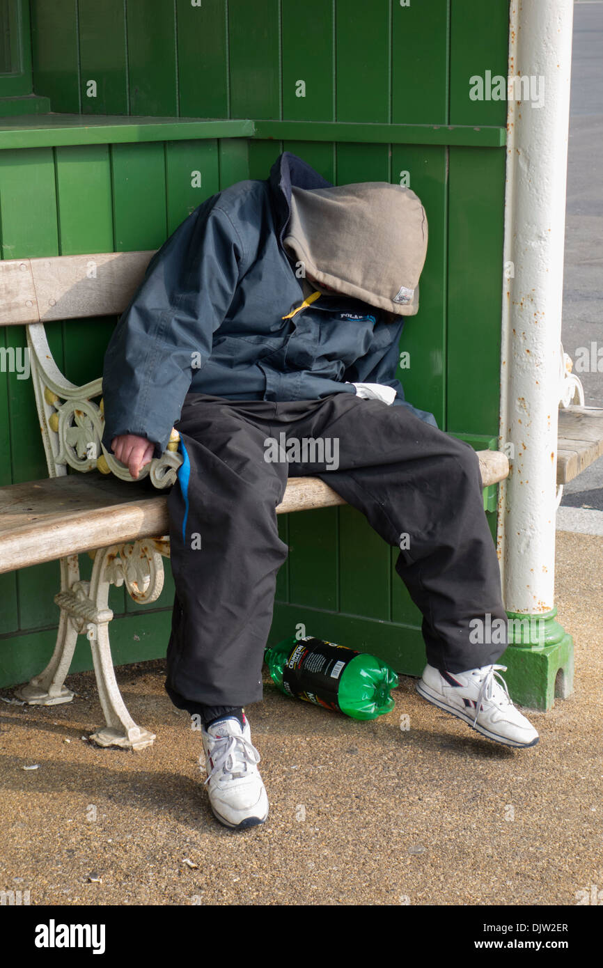 Una persona senza dimora addormentato su un banco in un rifugio sulla Promenade di Blackpool. Foto Stock