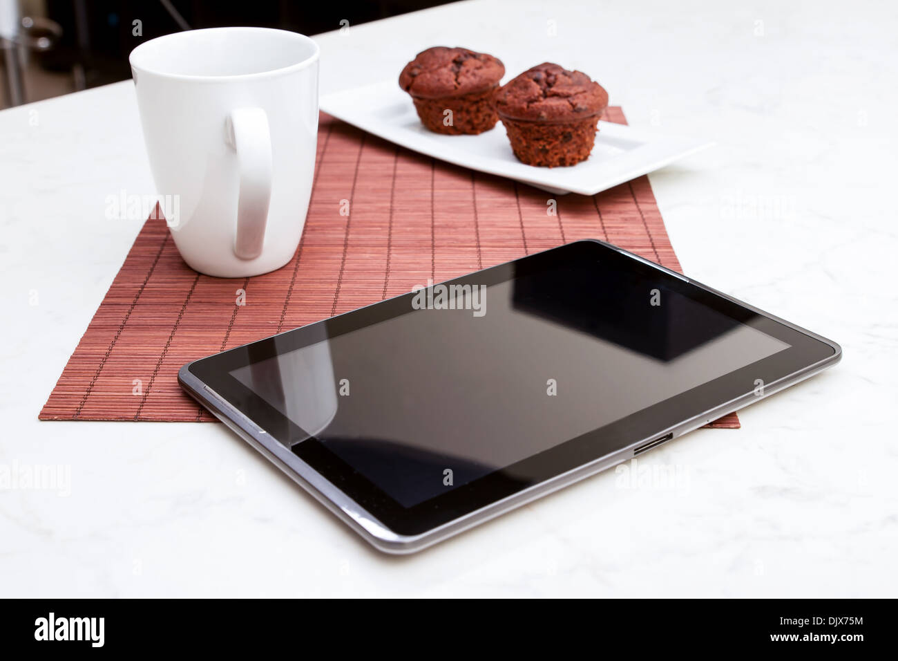 Gocce di cioccolato muffin con una tazza di caffè nel frattempo utilizzando il tablet PC. Foto Stock