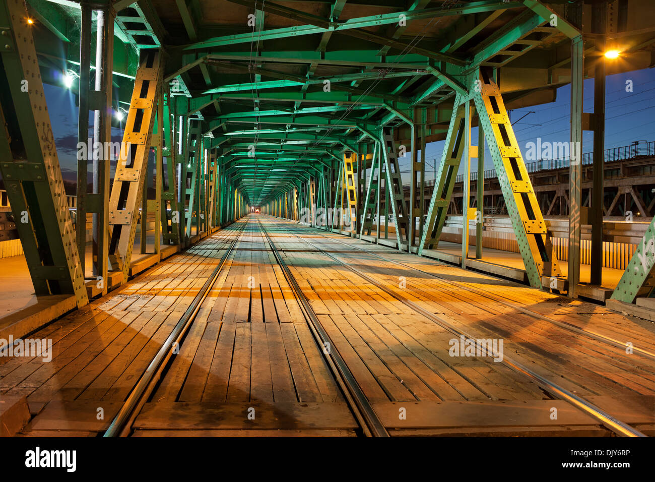 Tramvia con due tracce nella parte inferiore della travatura reticolare in acciaio ponte Gdanski a Varsavia, Polonia, illuminazione notturna. Foto Stock