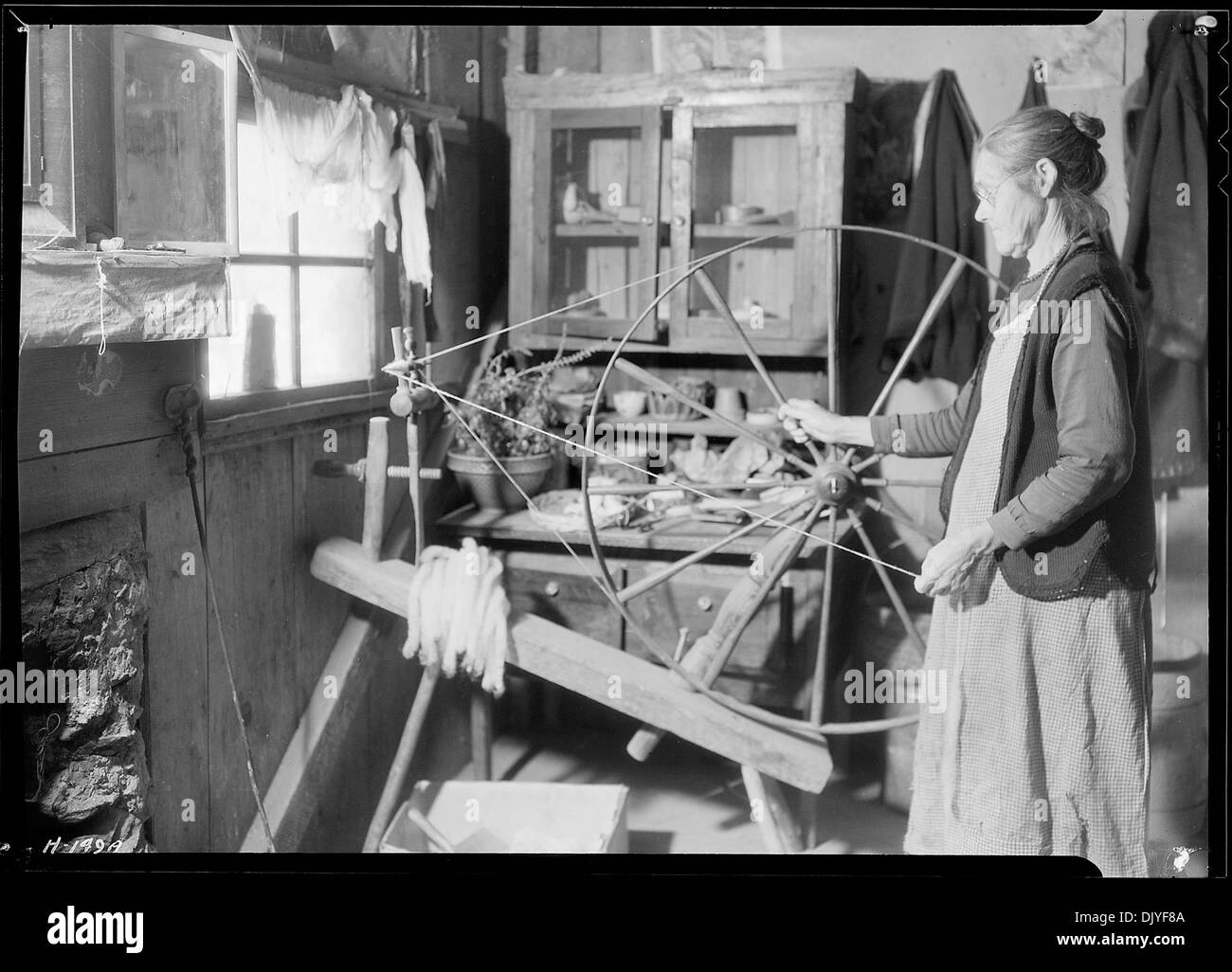 Questa fotografia mostra la signora James Watson alla sua ruota rotante nella sua cabina di montagna vicino a Gatlinburg, Tennessee. L'immagine cattura un momento di vita quotidiana in un ambiente rurale, appalachiano, mettendo in risalto l'artigianato tradizionale e la vita domestica della zona. Foto Stock