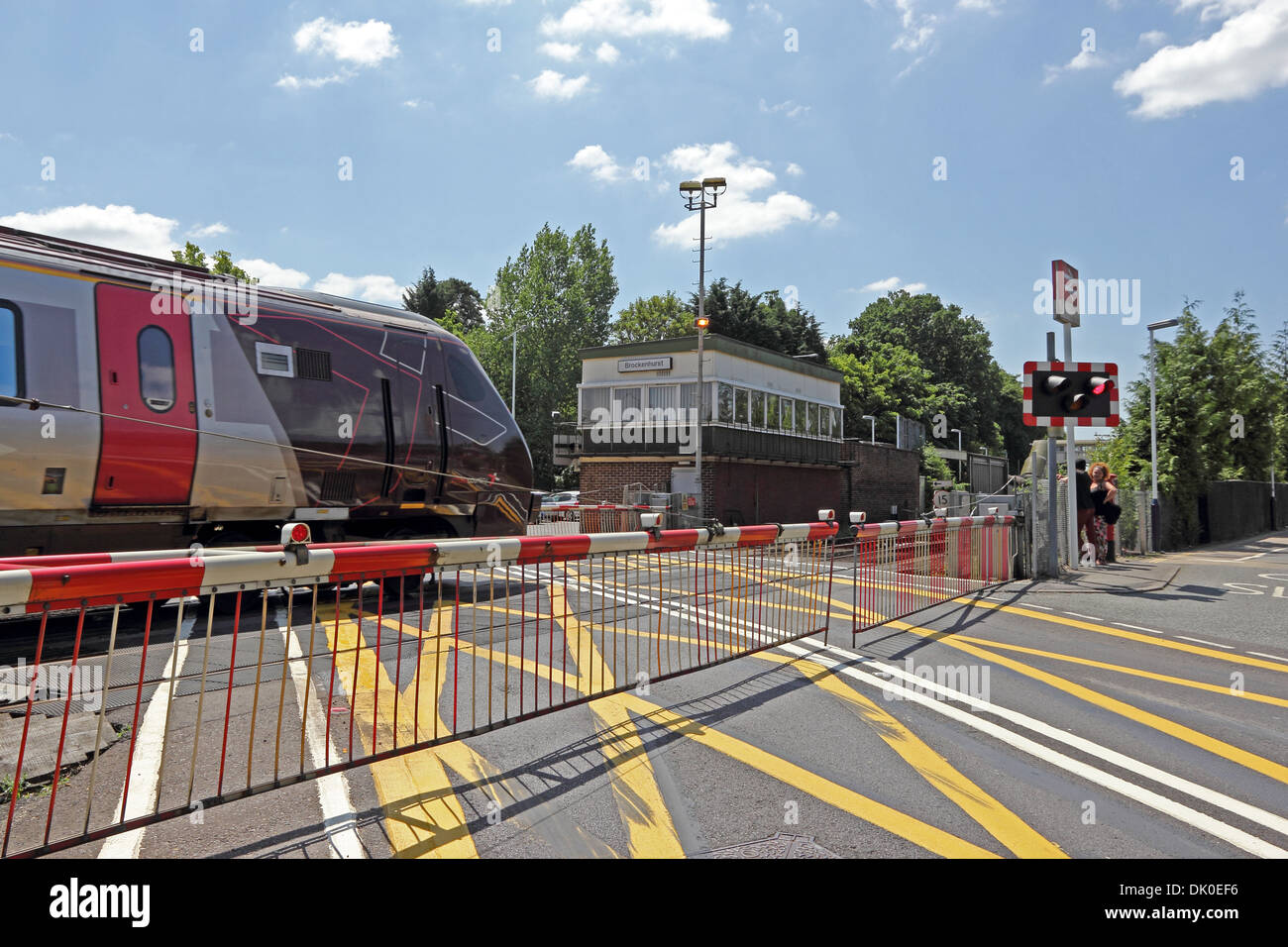 Passaggio a livello ferroviario a Brockenhurst station, con saracinesche abbassate come Cross Country treno passa Foto Stock