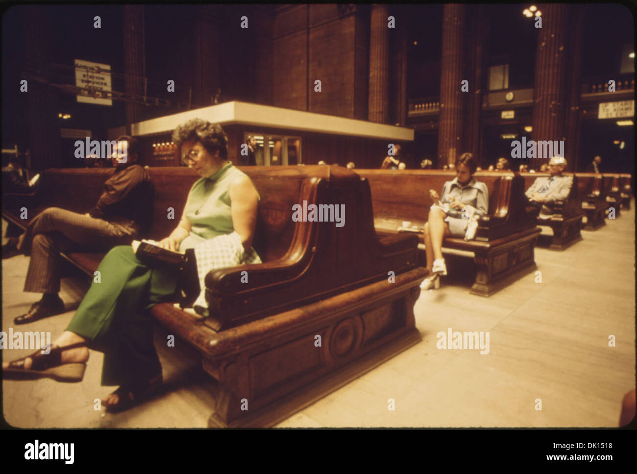 Questa foto mostra i passeggeri seduti su grandi panchine di legno alla Chicago Union Station, mettendo in risalto il grande stile architettonico della stazione. Le panchine si fondono con gli interni cavernosi della stazione, mostrando il suo design e la sua funzione storici. Foto Stock