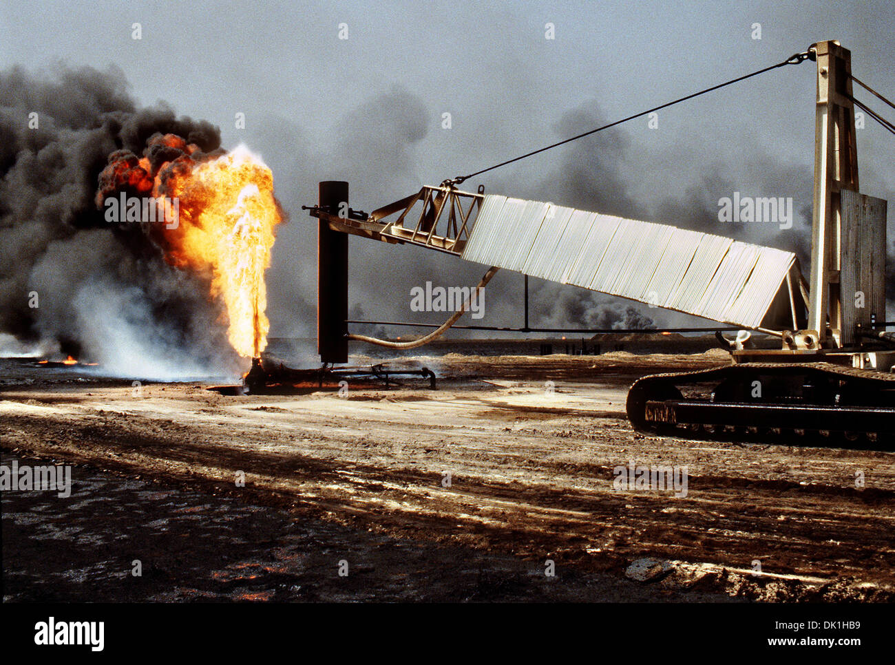 Vigili del fuoco da gli stivali e folaghe olio e lotta antincendio azienda di utilizzare una gru per cap a blazing olio bene all indomani dell Operazione Desert Storm Aprile 7, 1991 in Ahman campi petroliferi in Kuwait. Il pozzo, situato nell'olio di Ahman campi, è uno dei molti mise in fiamme da forze irachene prima del loro ritiro dal Kuwait. Foto Stock