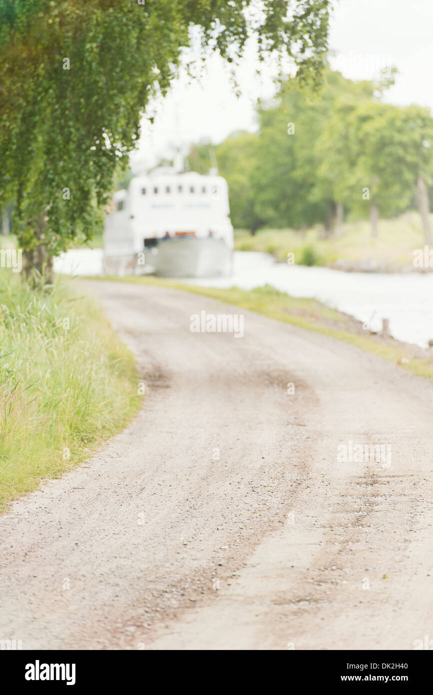 Tranquillo paesaggio estivo. Strada rurale e nave passeggeri su Gota Canal in Svezia. Foto Stock