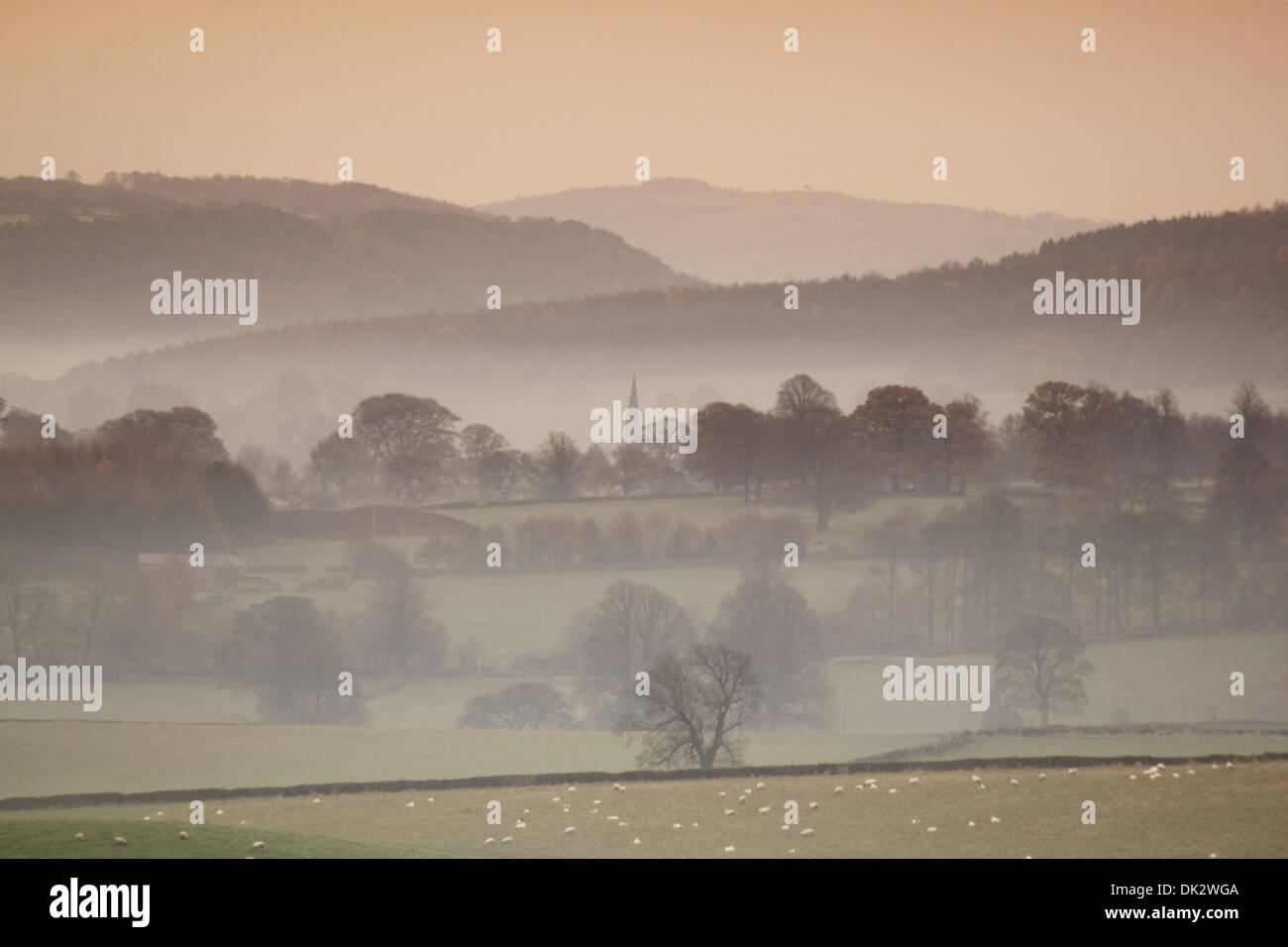 Foschia mattutina nel Peak District, Derbyshire affacciato sul villaggio di Edensor sul Chatsworth Station Wagon Foto Stock