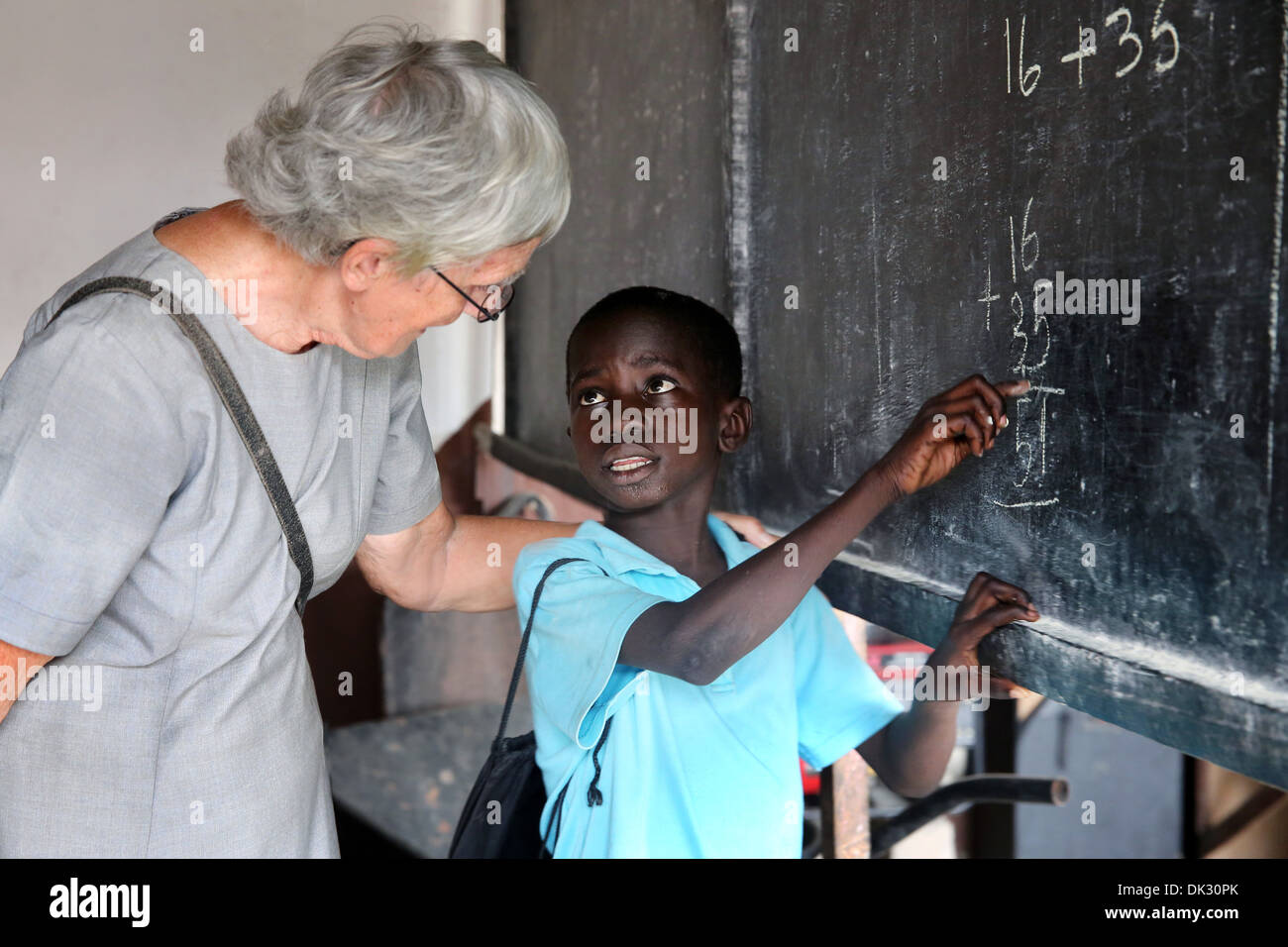Black Boy e insegnante di bianco in una classe di una scuola di volontariato gestiti dalla Chiesa cattolica. Accra, Africa occidentale Foto Stock