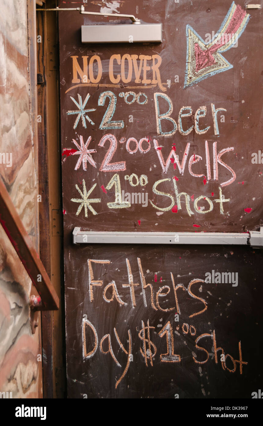 Uscita di emergenza con lavagna vernice usata per annunciare le offerte speciali del giorno in un bar locale in Fort Worth Stock cantieri. Foto Stock