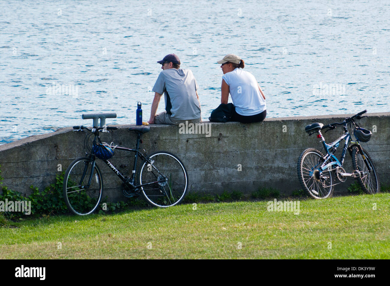 2 giovani resto sul lago dopo escursioni in bicicletta, Seattle, nello stato di Washington, Stati Uniti d'America Foto Stock