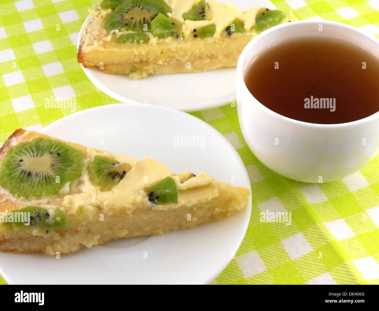 Una tazza di tè e un pezzo di gustosa torta cremosa con frutti Foto Stock