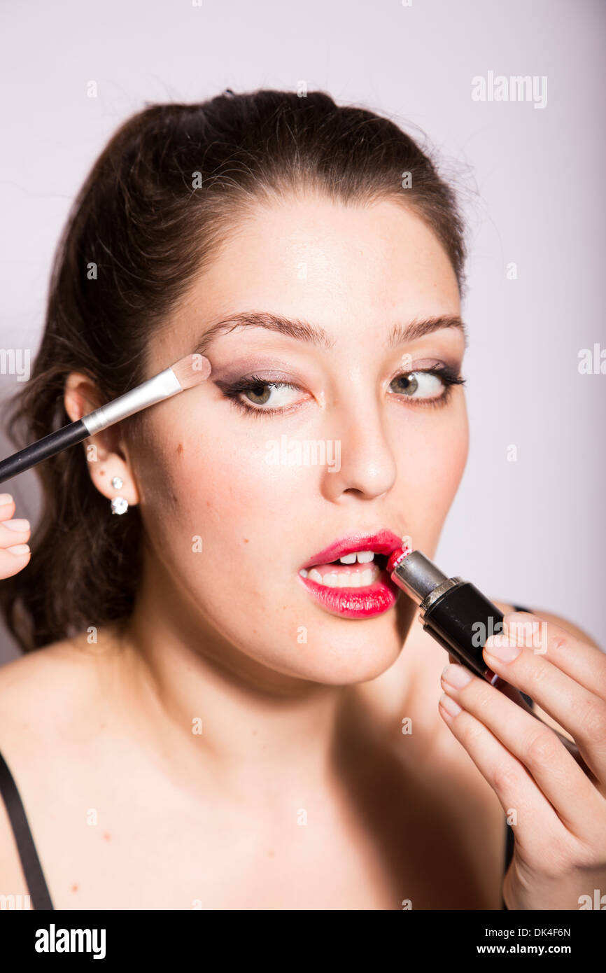 Giovane donna si applica eye shadow e il rossetto Foto Stock