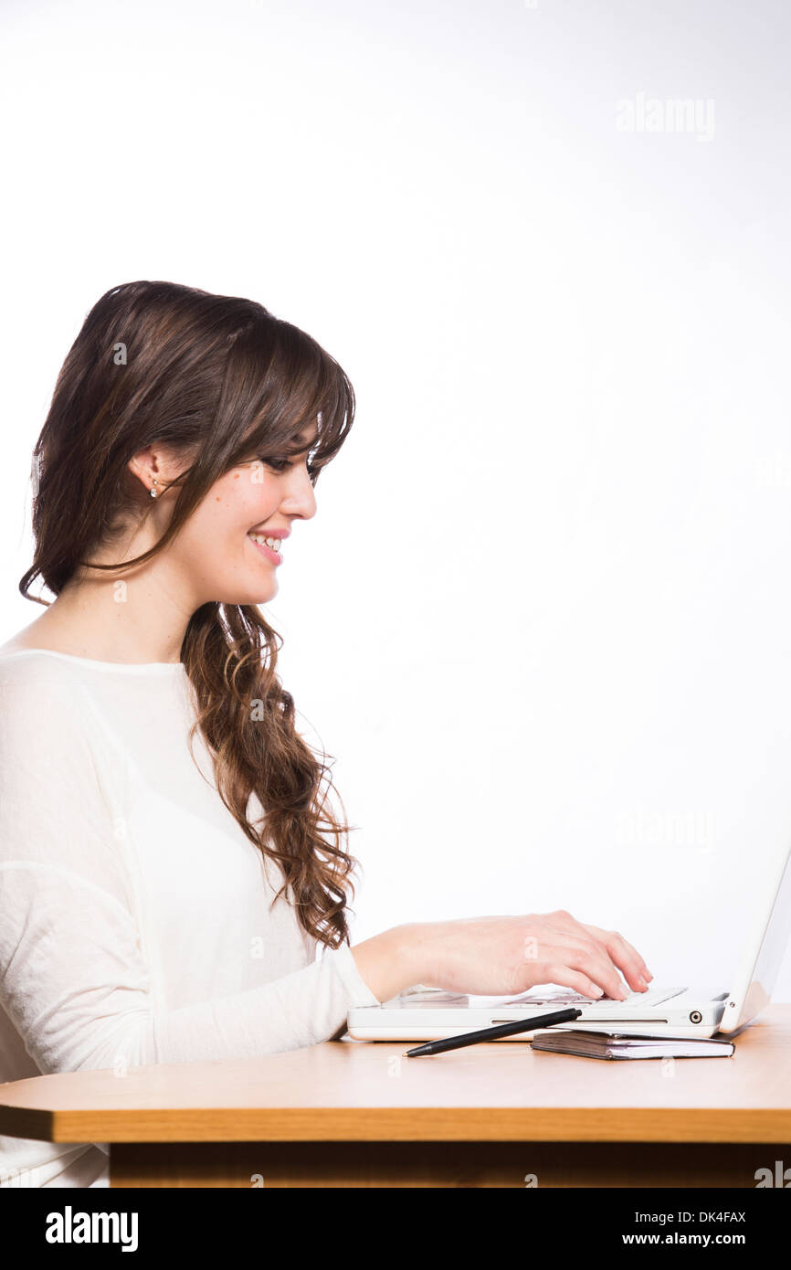 Giovane donna alla scrivania con computer e caffè su sfondo bianco Foto Stock