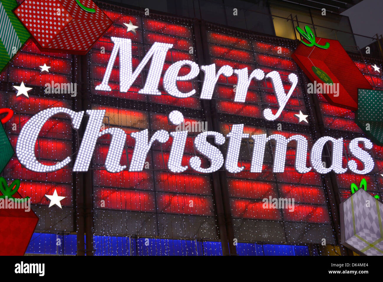 Primo piano su Merry segno di Natale decorazione in luci sul negozio Davanti all'edificio sopra l'ingresso di notte nel negozio Boots in West End Oxford Street Londra Regno Unito Foto Stock