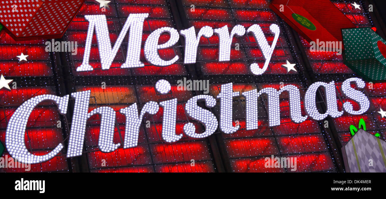 Primo piano su Merry segno di Natale decorazione in luci sul negozio Davanti all'edificio sopra l'ingresso di notte nel negozio Boots in West End Oxford Street Londra Regno Unito Foto Stock