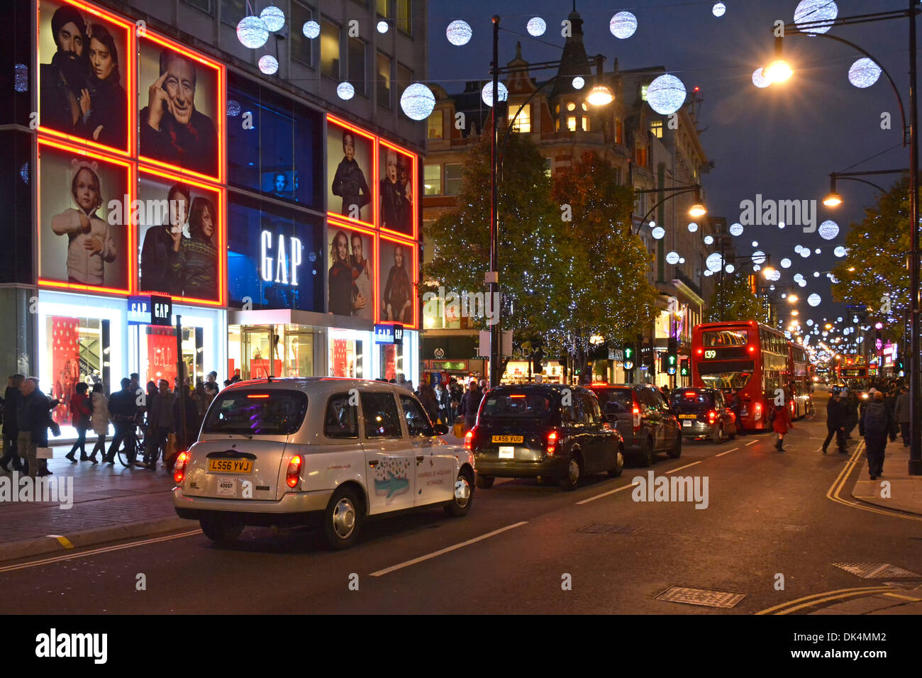 A Londra i taxi e gli autobus in coda in Oxford Street sotto le decorazioni di Natale Foto Stock