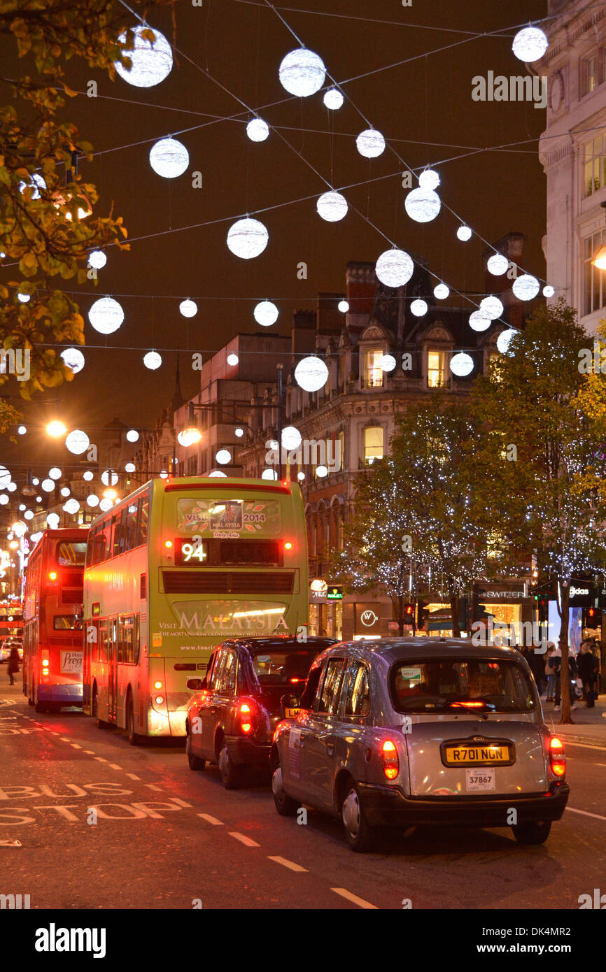 A Londra i taxi e gli autobus in Oxford Street sotto le decorazioni di Natale Foto Stock