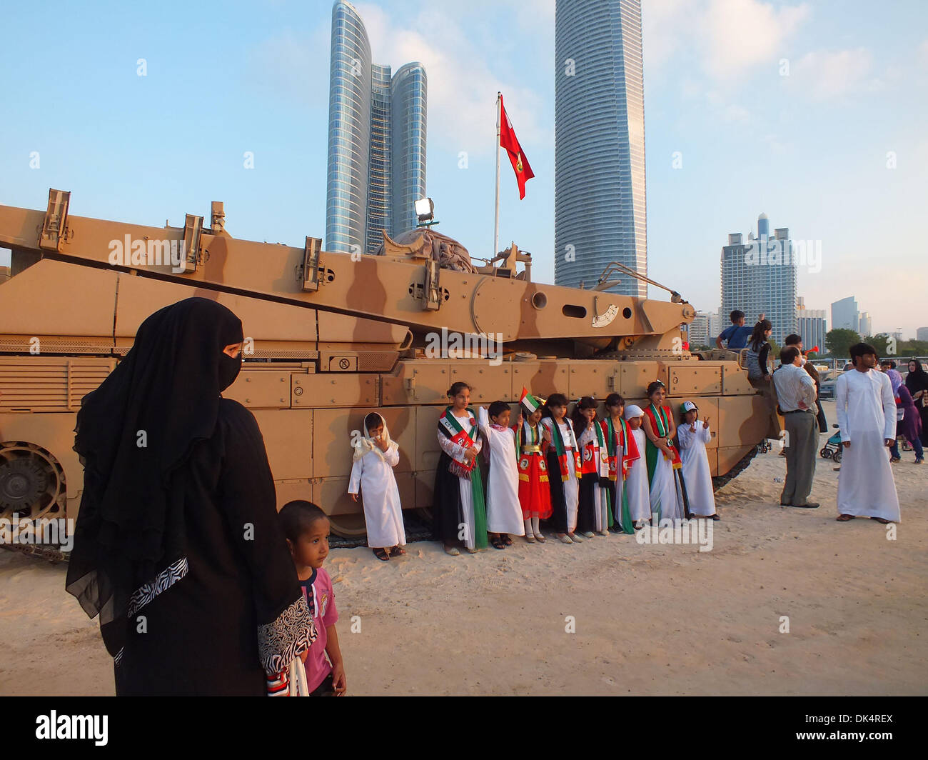 Abu Dhabi. 2° dic, 2013. I bambini rappresentano per le foto nella parte anteriore di un veicolo armato soggetto alle forze armate di United Arab Emirates di (UAE) durante un militare di spettacolo presentato dagli Emirati forze militari per celebrare il UAE XLII Giornata Nazionale di Abu Dhabi, Emirati arabi uniti, Dicembre 2, 2013. (Xinhua/Ma Xiping) Foto Stock