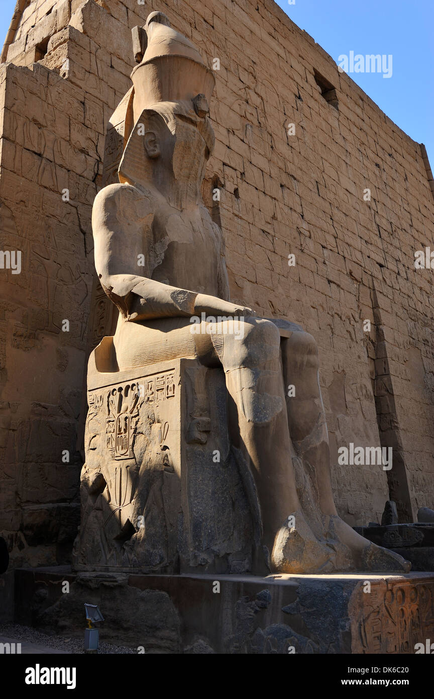 Seduto Statua di Ramesse II e il primo pilone in entrata al Tempio di Luxor - Luxor, Egitto Foto Stock