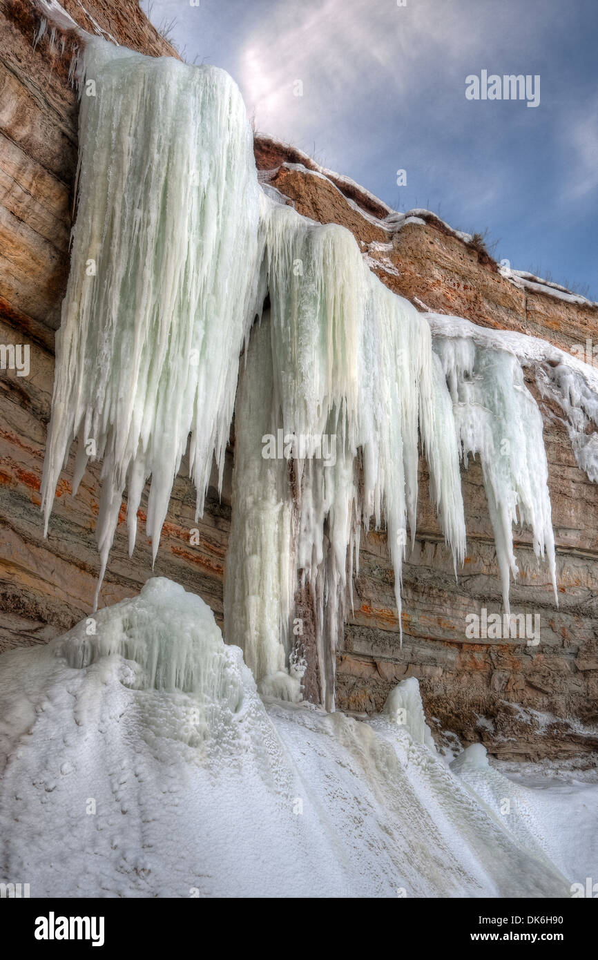 Tall ghiaccioli appesi su di una scogliera in inverno Foto Stock