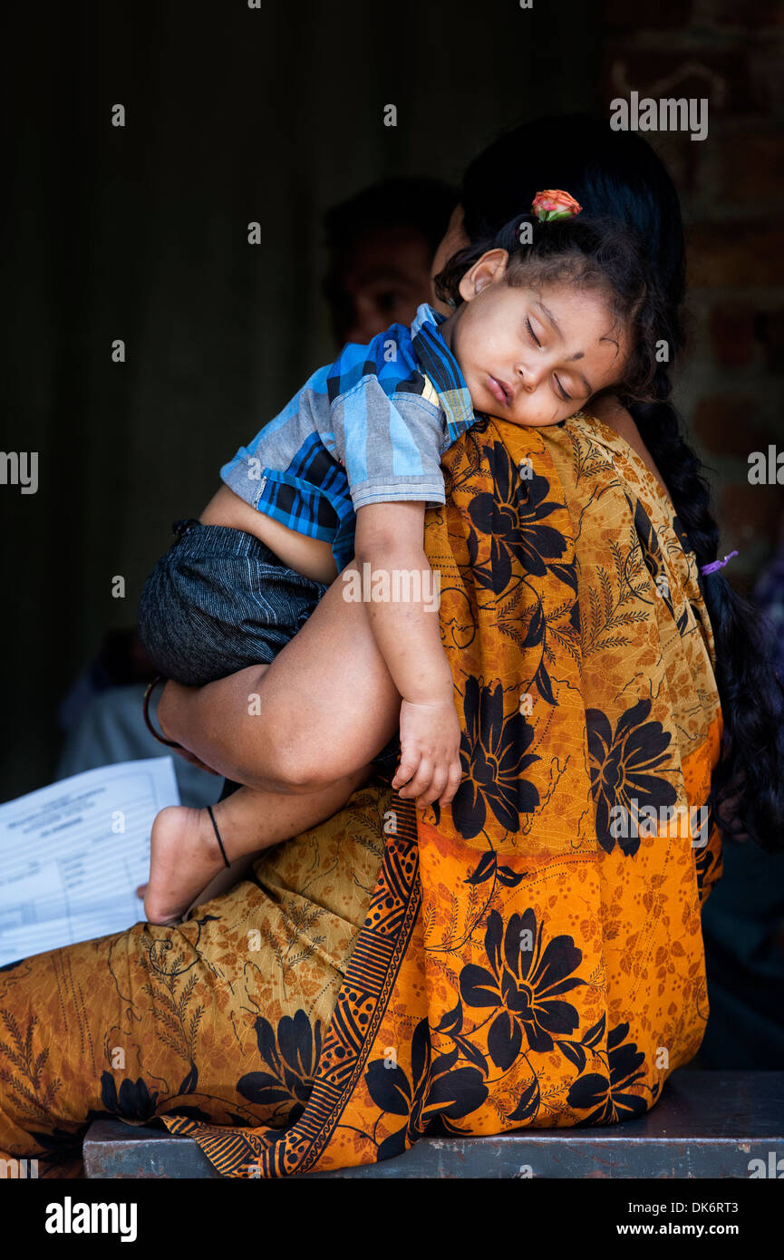 Giovani indiani bambina di dormire sulla sua spalla le madri in una zona rurale villaggio indiano. Andhra Pradesh, India Foto Stock