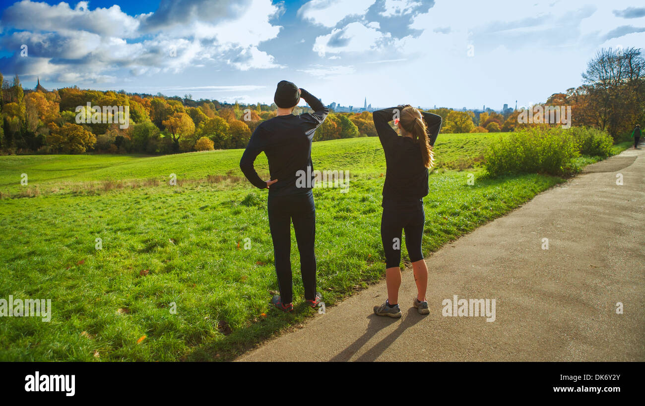 Due giovani adulti prendere in autunno vista su Hampstead Heath verso la lontana città di Londra. Foto Stock