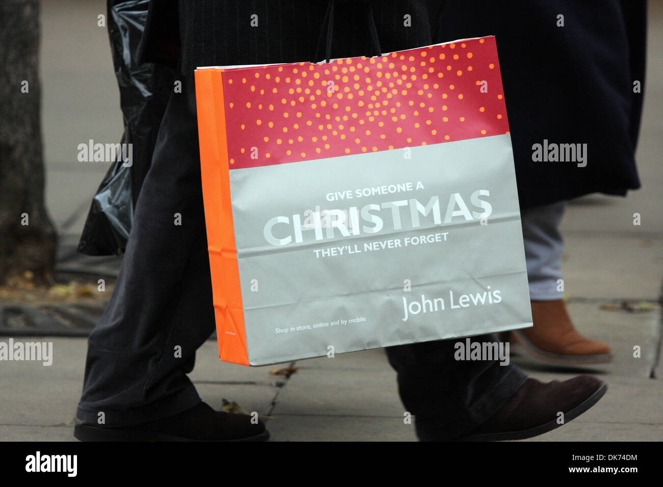 Parte di una persona che porta un John Lewis Christmas shopping bag in Oxford Street a Londra, Inghilterra Foto Stock