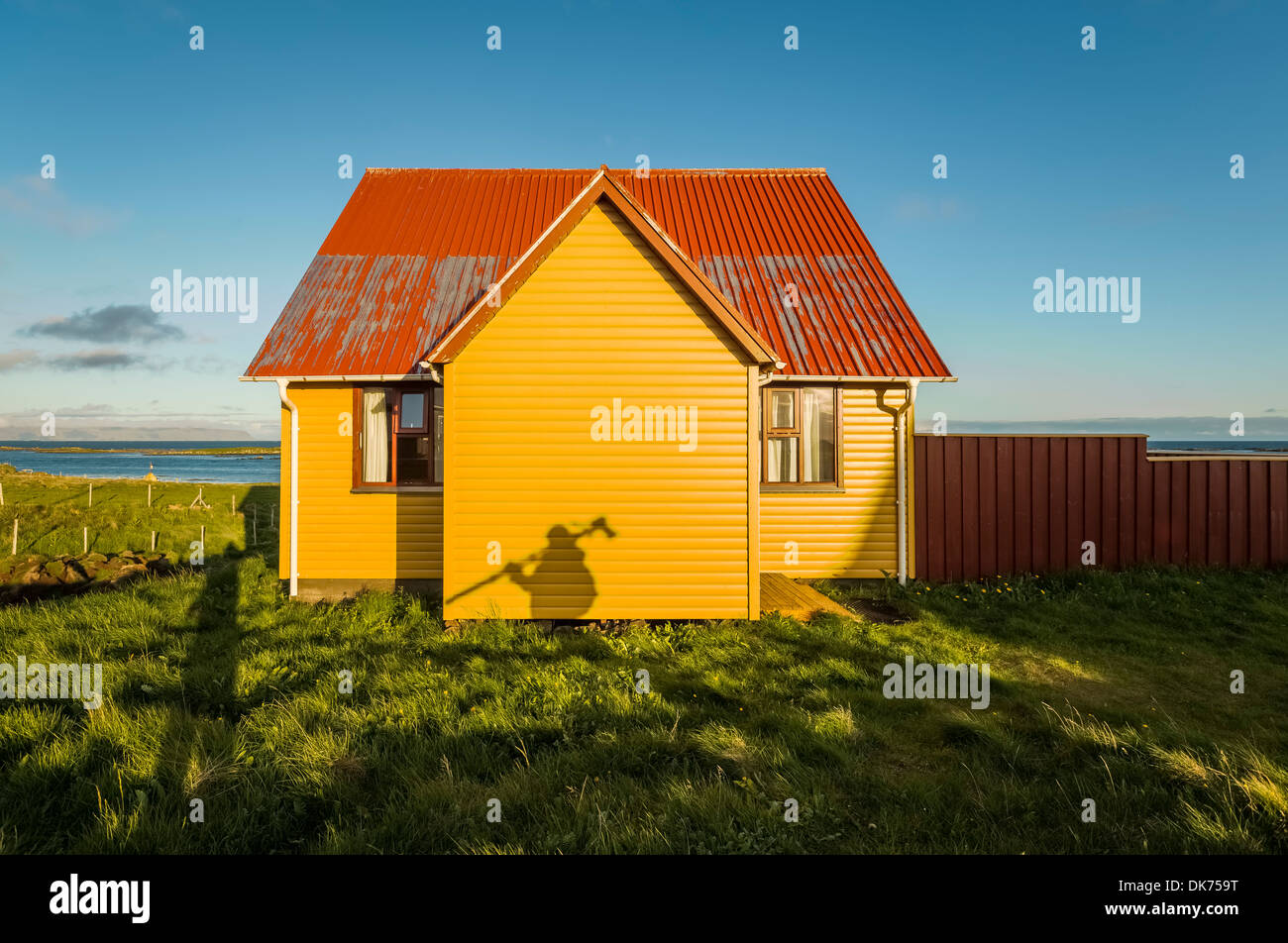 Ombra del fotografo con il treppiede su casa estiva, Flatey Isola, Breidafjordur, Islanda Foto Stock