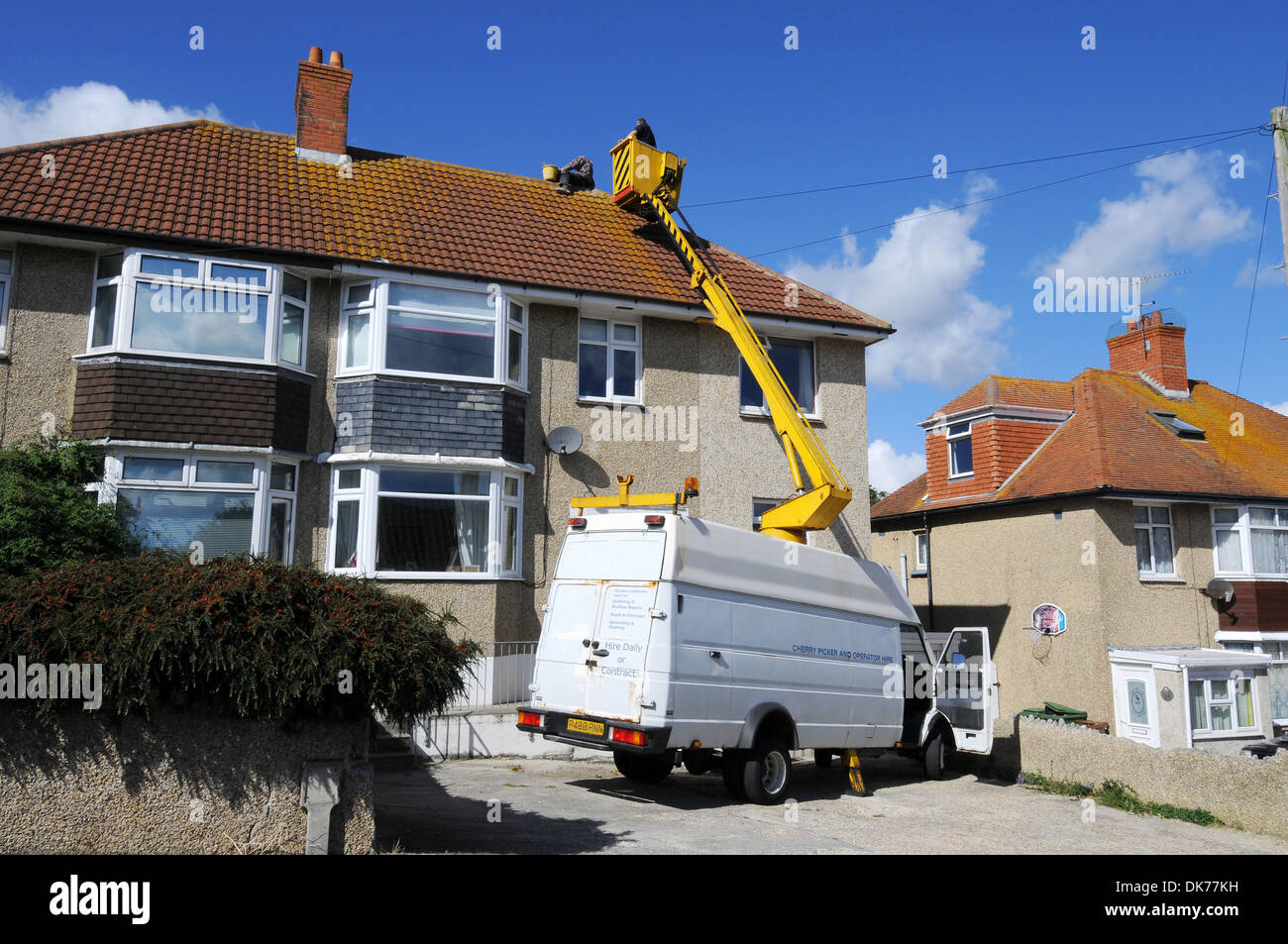 Le riparazioni del tetto, operai riparando il tetto con un 'cherry picker' in Gran Bretagna, Regno Unito Foto Stock