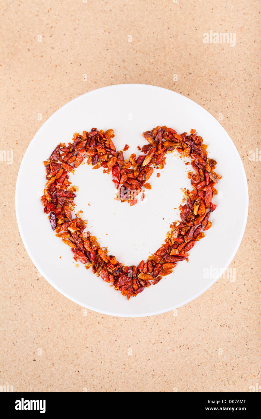Amore caldo concetto, peperoncino rosso sulla lastra disposta in forma di cuore. Foto Stock