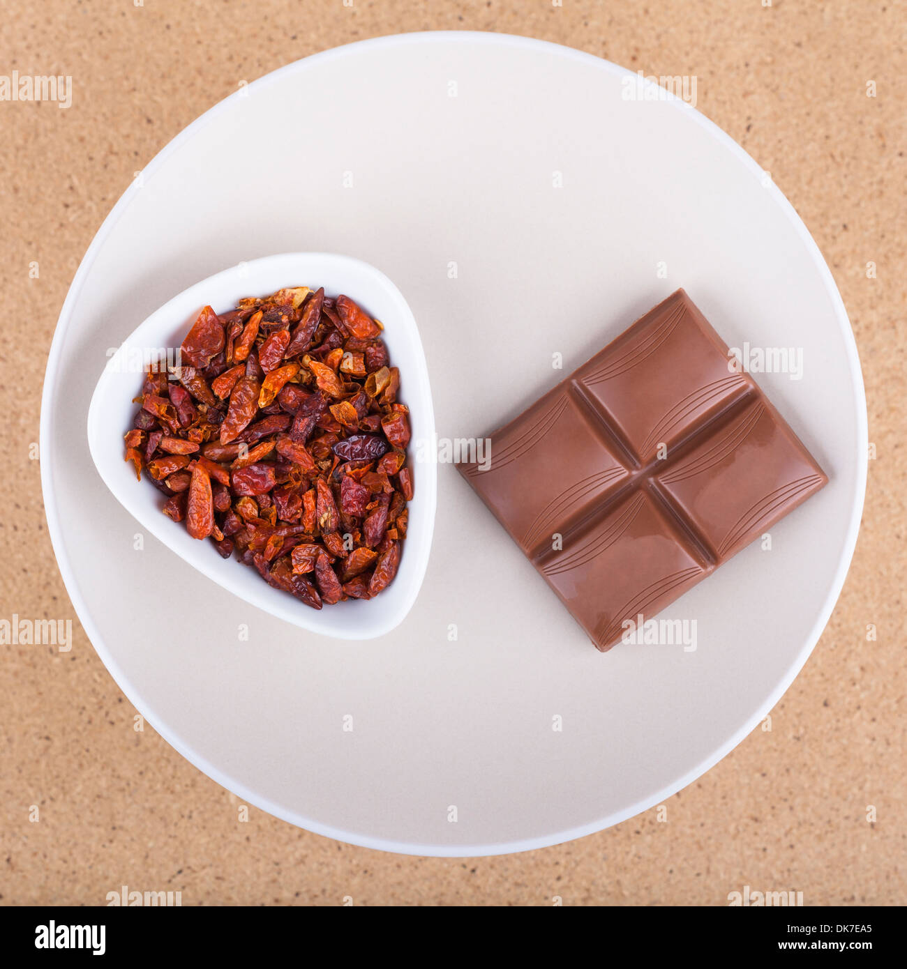 Essiccato red hot chili peppers con cioccolato sulla piastra, oltre la luce sullo sfondo di legno. Foto Stock