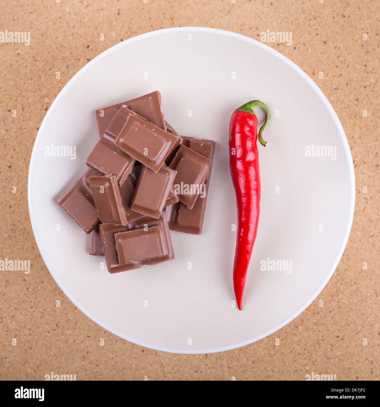Fresh red hot chili pepper con cioccolato sulla piastra, su sfondo di legno. Foto Stock