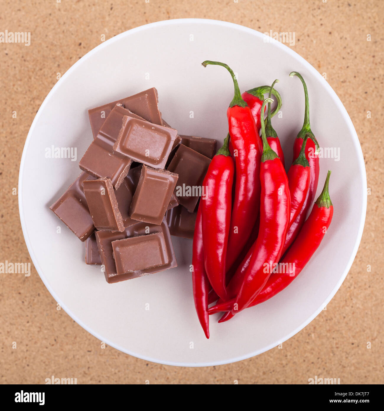 Fresh red hot chili peppers con cioccolato sulla piastra, su sfondo di legno. Foto Stock