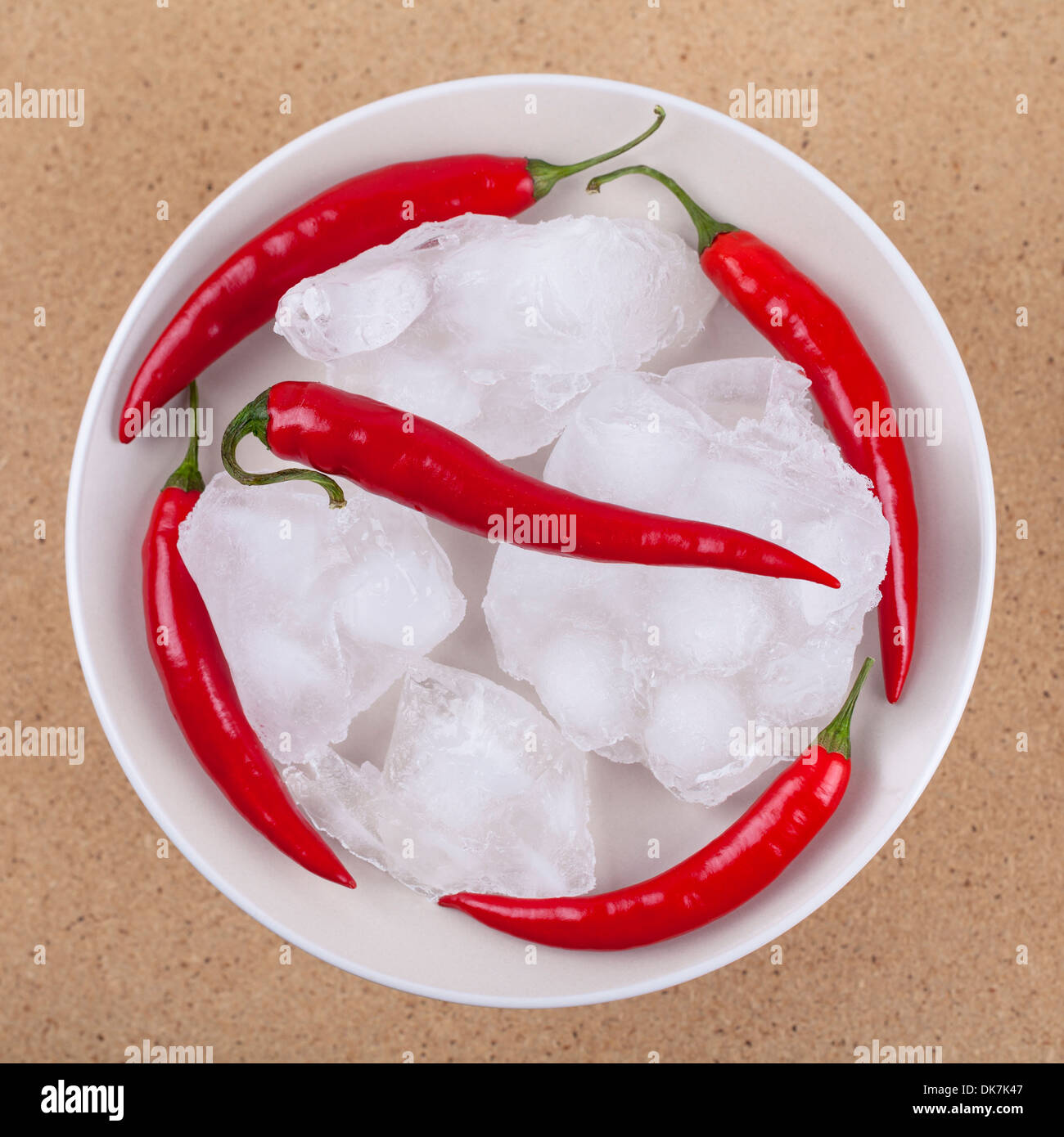 Fresh red hot chili peppers con ghiaccio sulla piastra, su sfondo di legno. Foto Stock