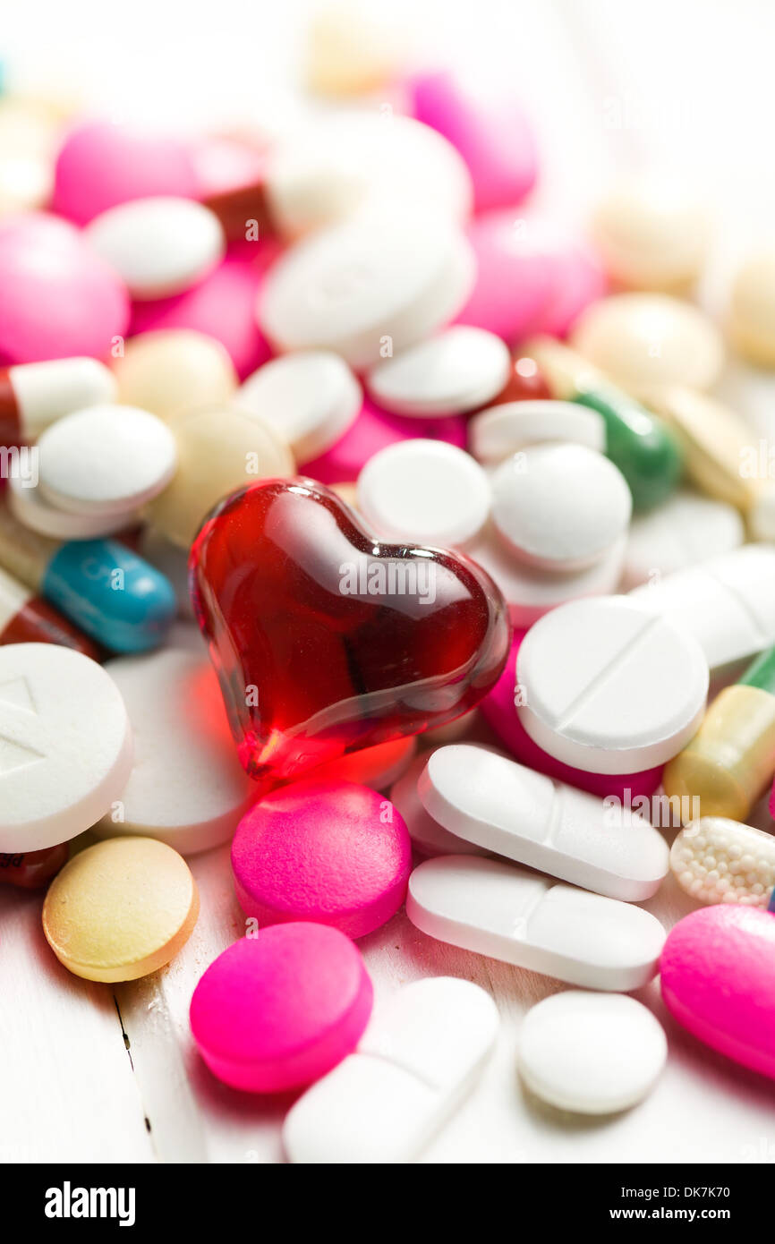 Pila di pillole colorate con cuore rosso Foto Stock