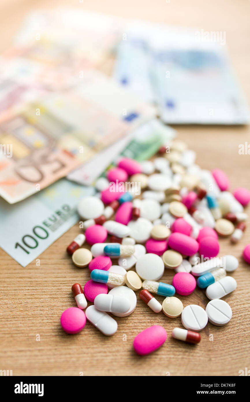 Pillole colorate con le fatture in euro sul tavolo di legno Foto Stock