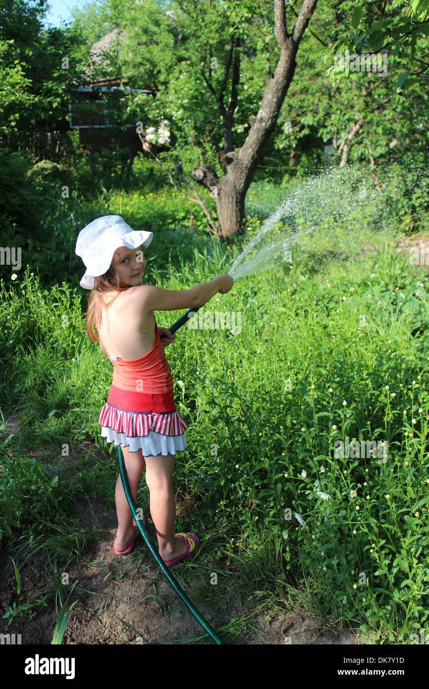 Irrigazione ragazza un orto nel paese Foto Stock