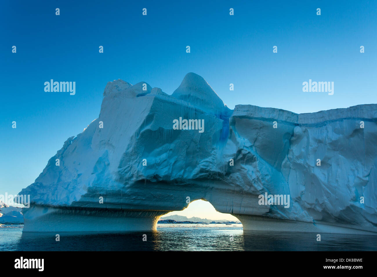 L'Antartide, Petermann Island, il sole di mezzanotte impostazione dietro arcuata di iceberg vicino al canale di Lemaire Foto Stock