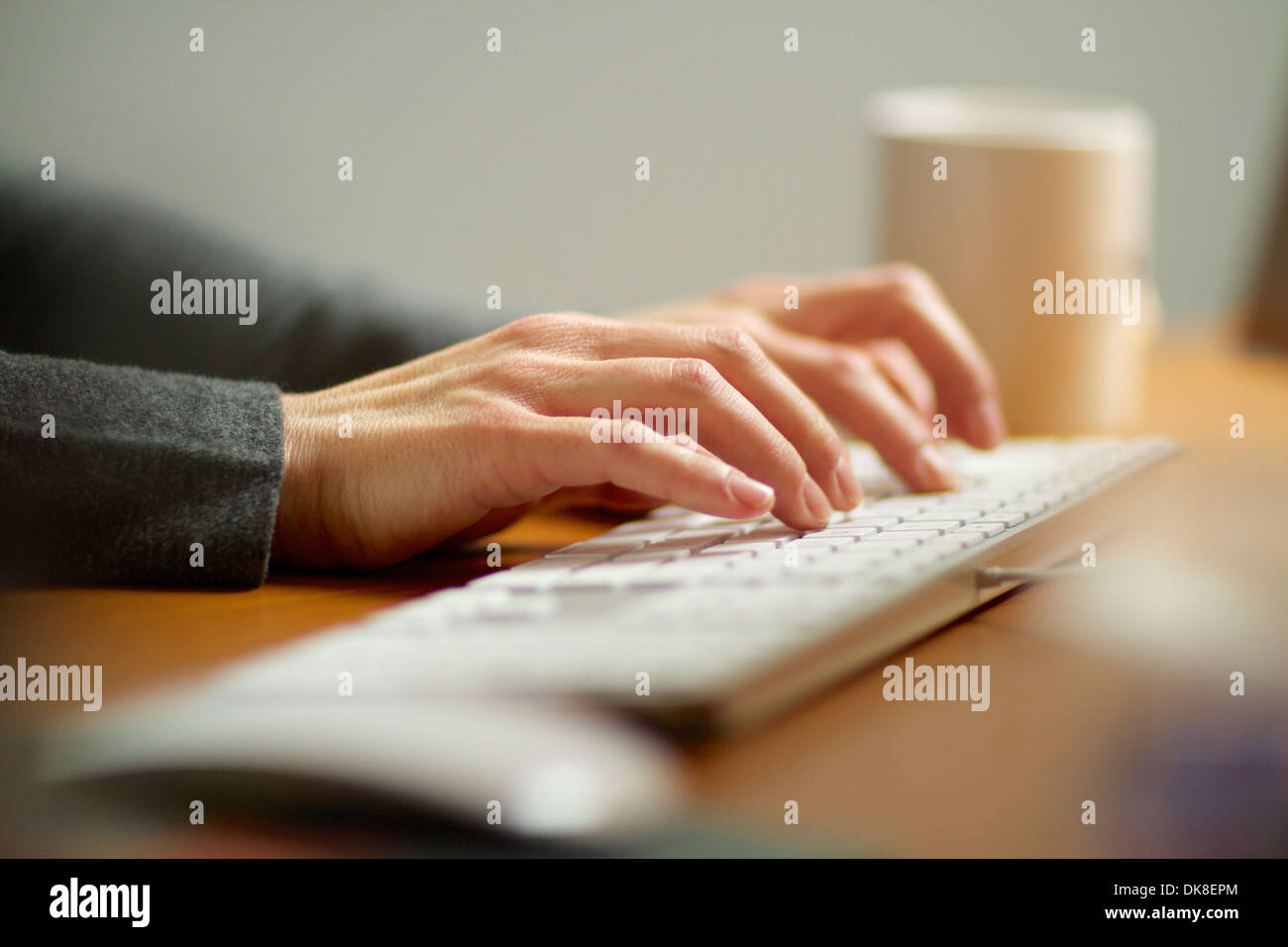 Mani femminili digitando su una tastiera di computer a lavorare nel suo ufficio. Foto Stock