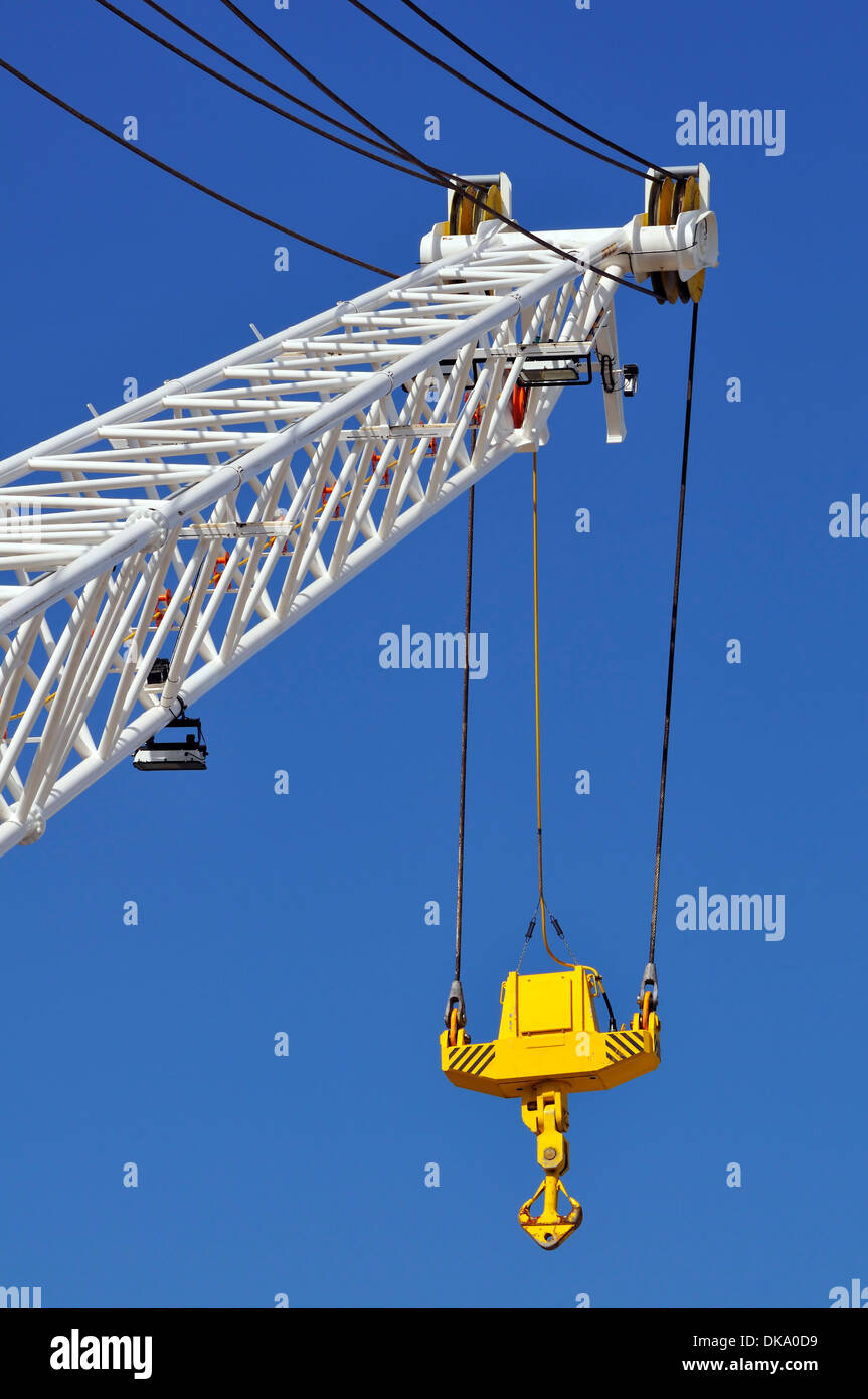 Braccio di gru con gancio giallo contro un cielo blu Foto Stock