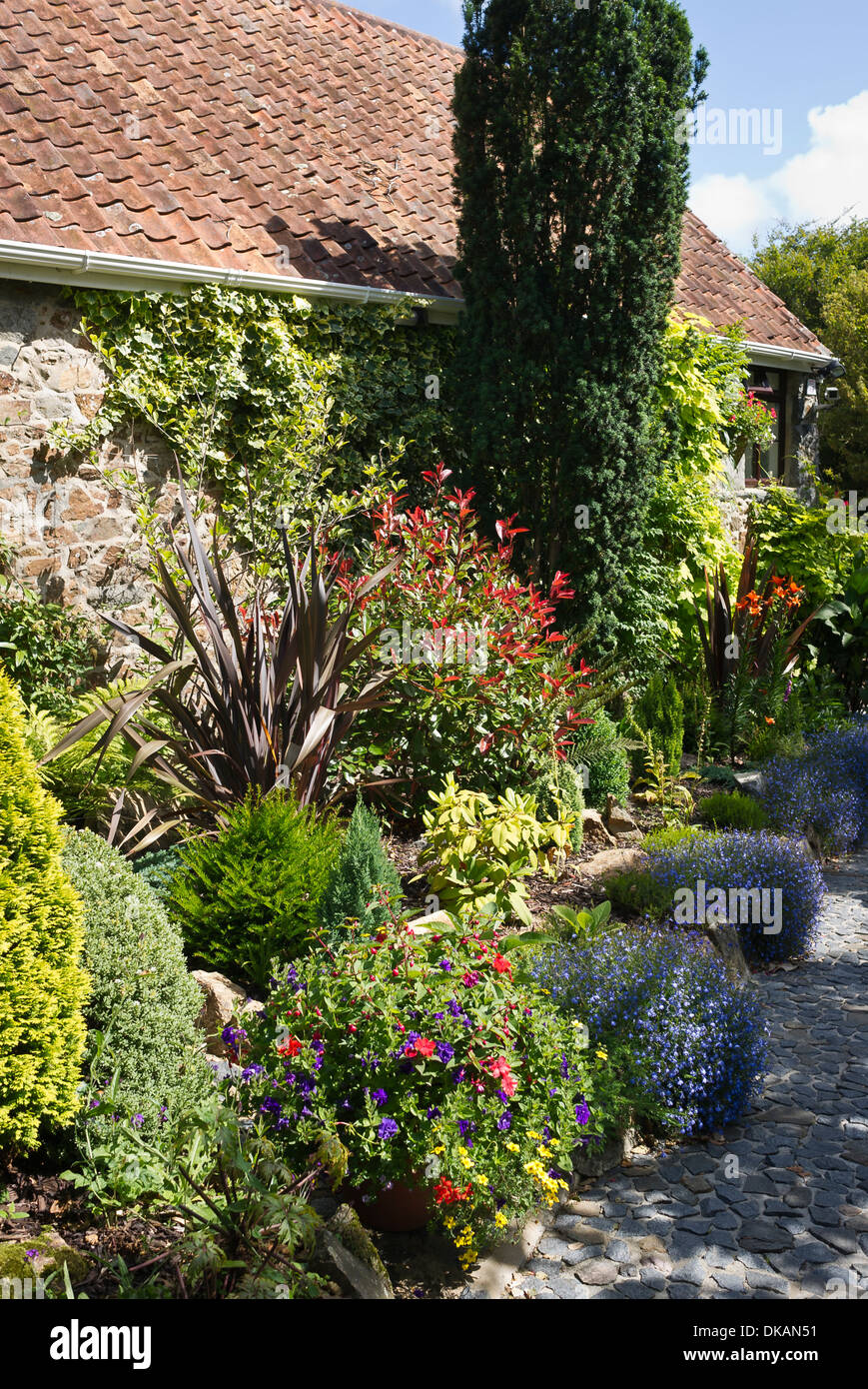 Un equilibrato stretti confini di fiori in un privato Guernsey giardino aperto al pubblico Foto Stock