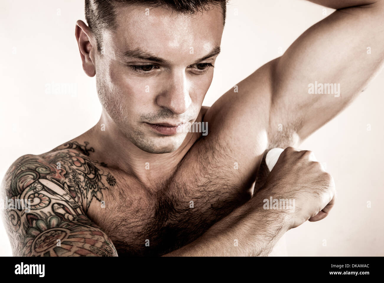 Studio shot di metà uomo adulto applicando deodorante Foto Stock