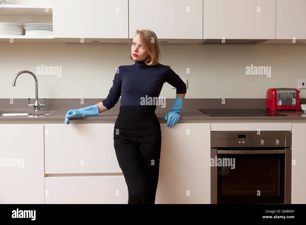 Donna appoggiata contro il mobile da cucina Foto Stock