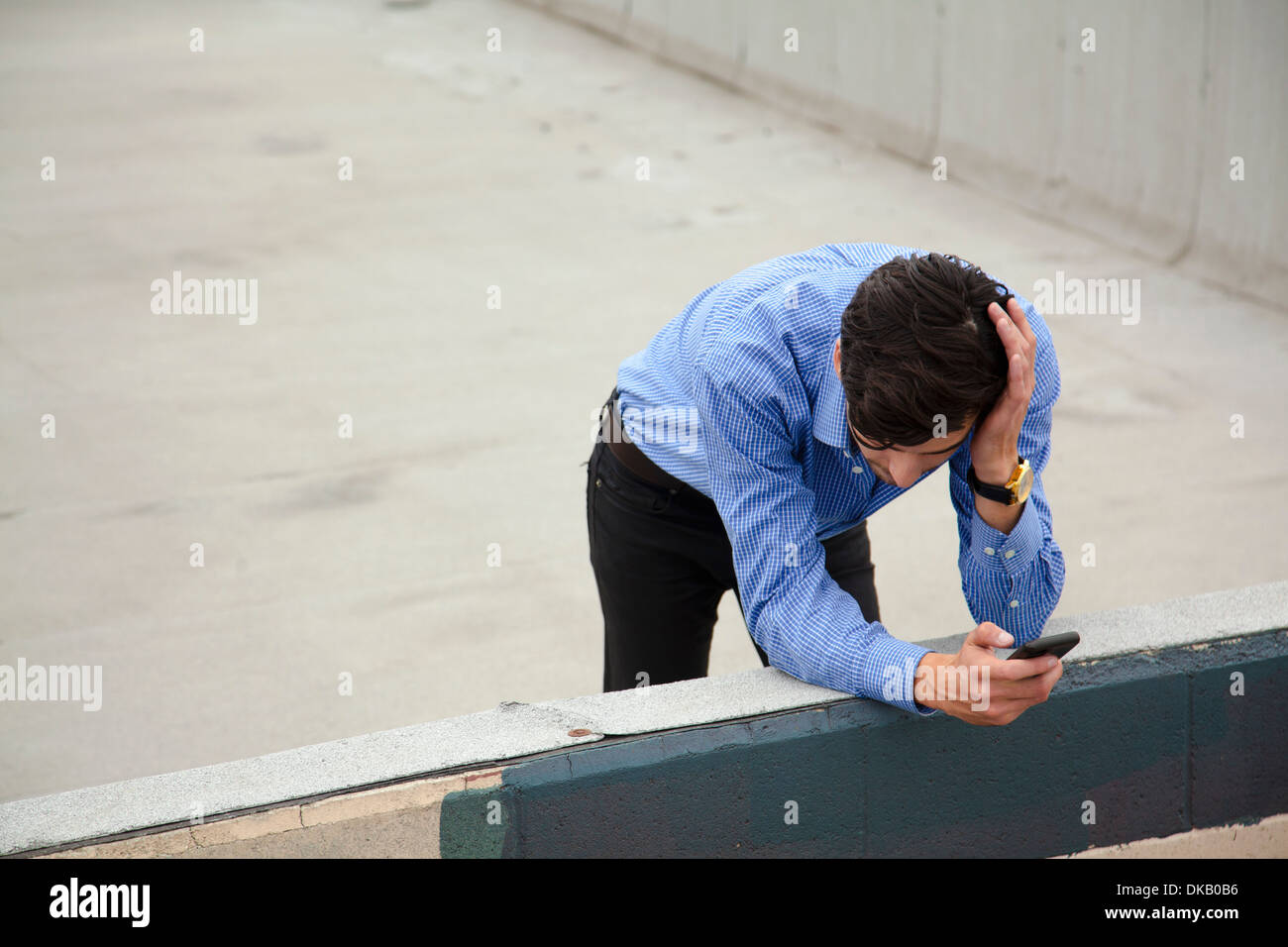 Ansioso giovane uomo appoggiato sulla parete sul tetto della città Foto Stock