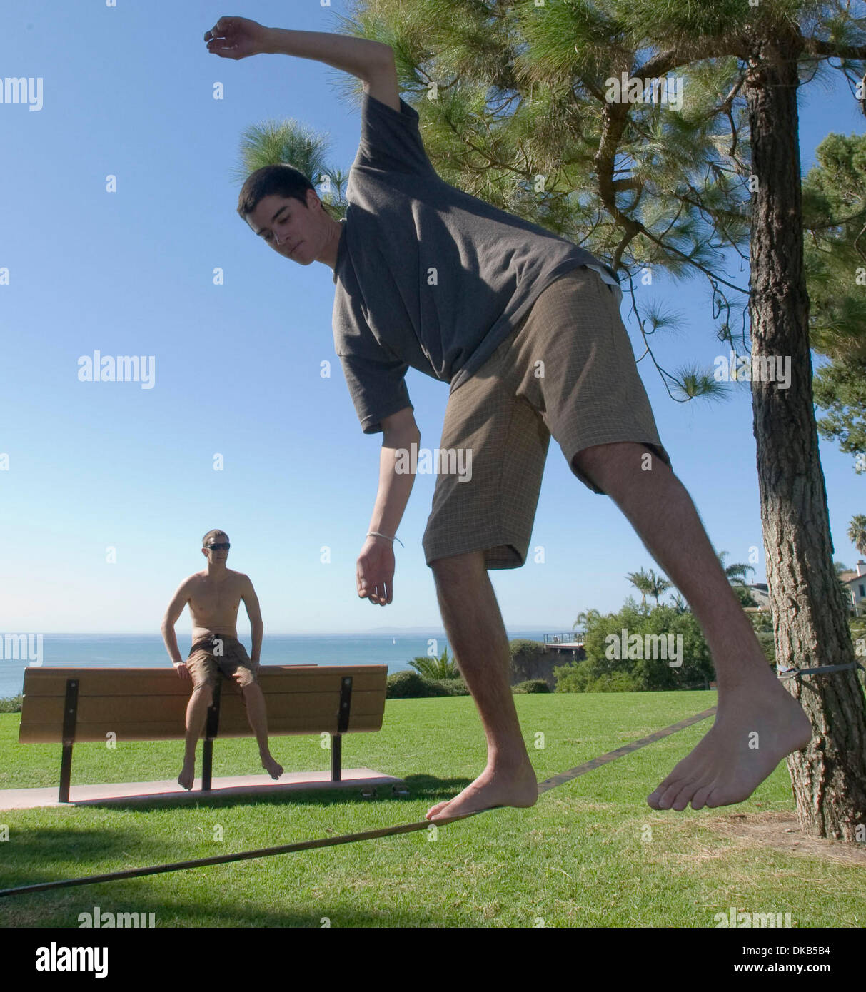 Sett. 28, 2011 - Dana Point, California, Stati Uniti - Un giovane uomo saldi su una fune lui e un amico hanno legato circa 2 piedi dal suolo tra due alberi di pino in un sempre più popolari attività denominata 'slacklining,' in un piccolo parco in Dana Point. Slacklining è inteso per la sintonizzazione fine, coordinamento, di equilibrio e di fiducia per non solo di alpinismo ma anche di sport come il surf, volle Foto Stock