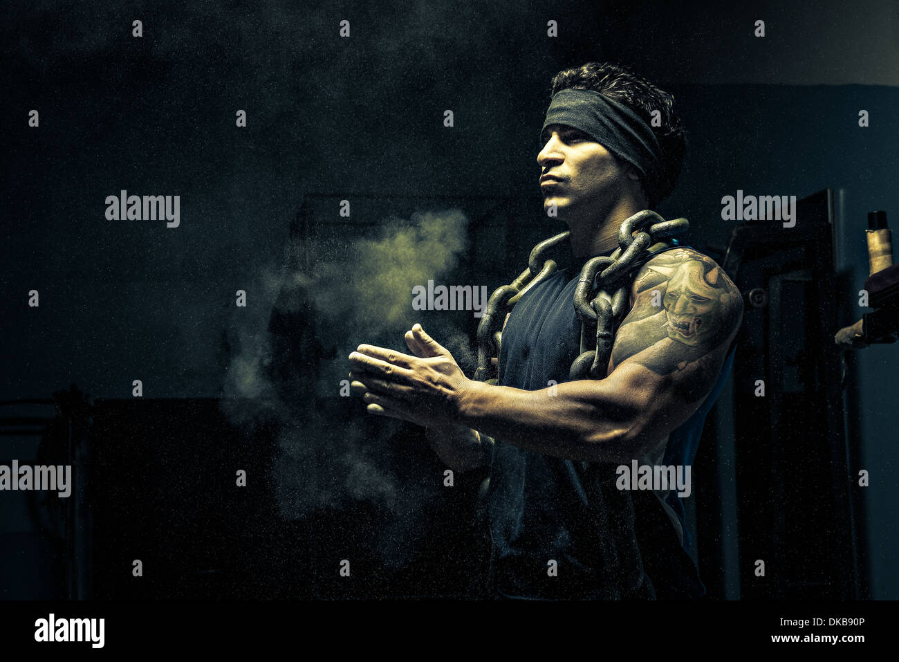 Weightlifter in dark palestra, mettendo chalk sulle mani Foto Stock