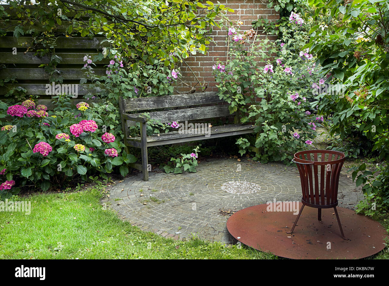 In stile country con giardino panca, caminetto e un sacco di fiori in estate Foto Stock