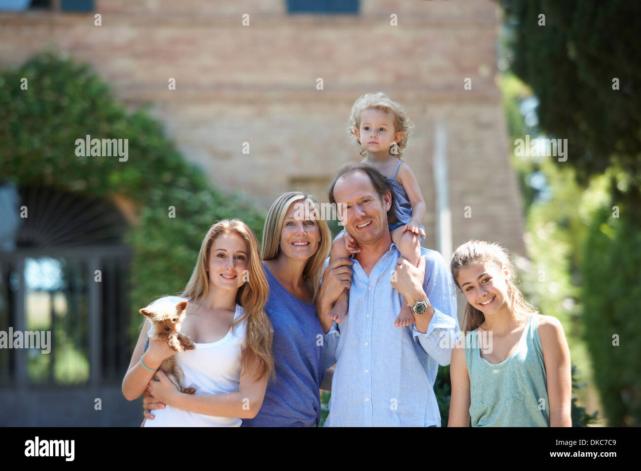 I genitori in piedi con le figlie e il cane in giardino Foto Stock