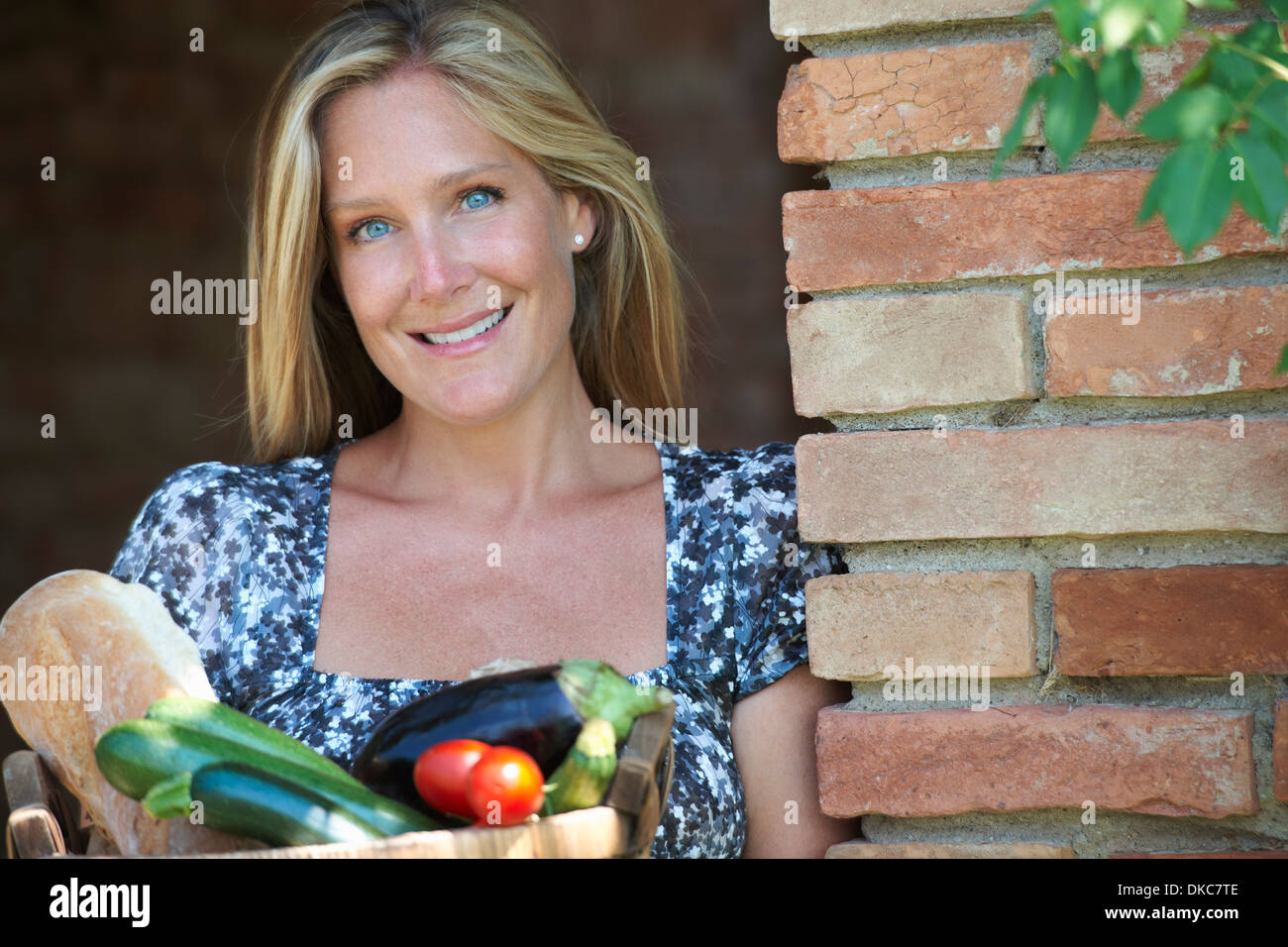 Donna matura in piedi fuori con cesto di alimenti biologici Foto Stock